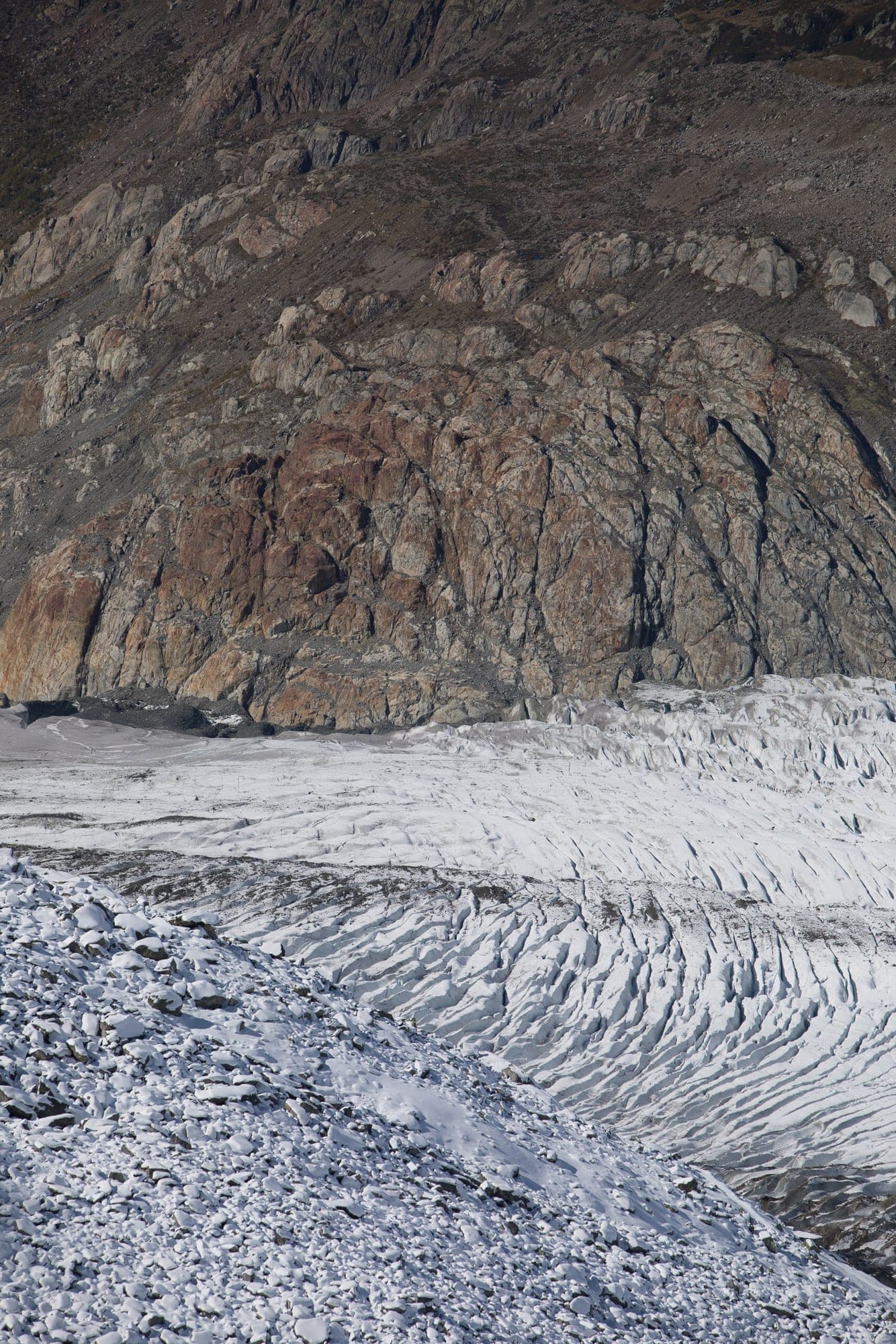 The cracked tongue of a glacier spilling over a dark rock cliff in Wallis.