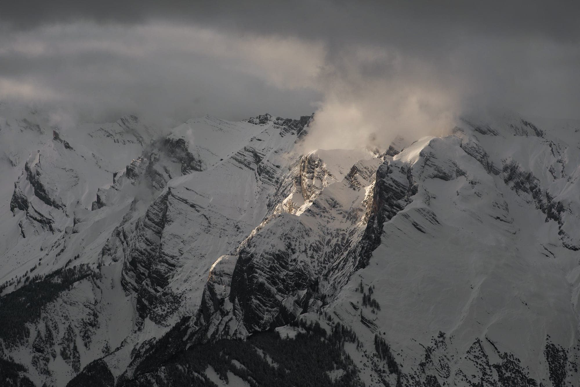 A snow-covered massif catching the last warm light of the day above valleys already in shadow, in Wallis.