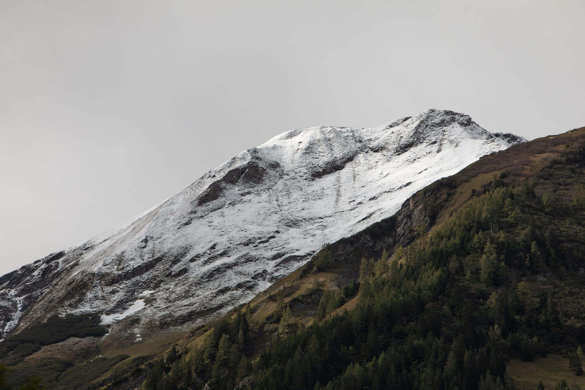 A snow-capped peak under a heavy grey sky, its summit half lost in cloud, in Wallis.