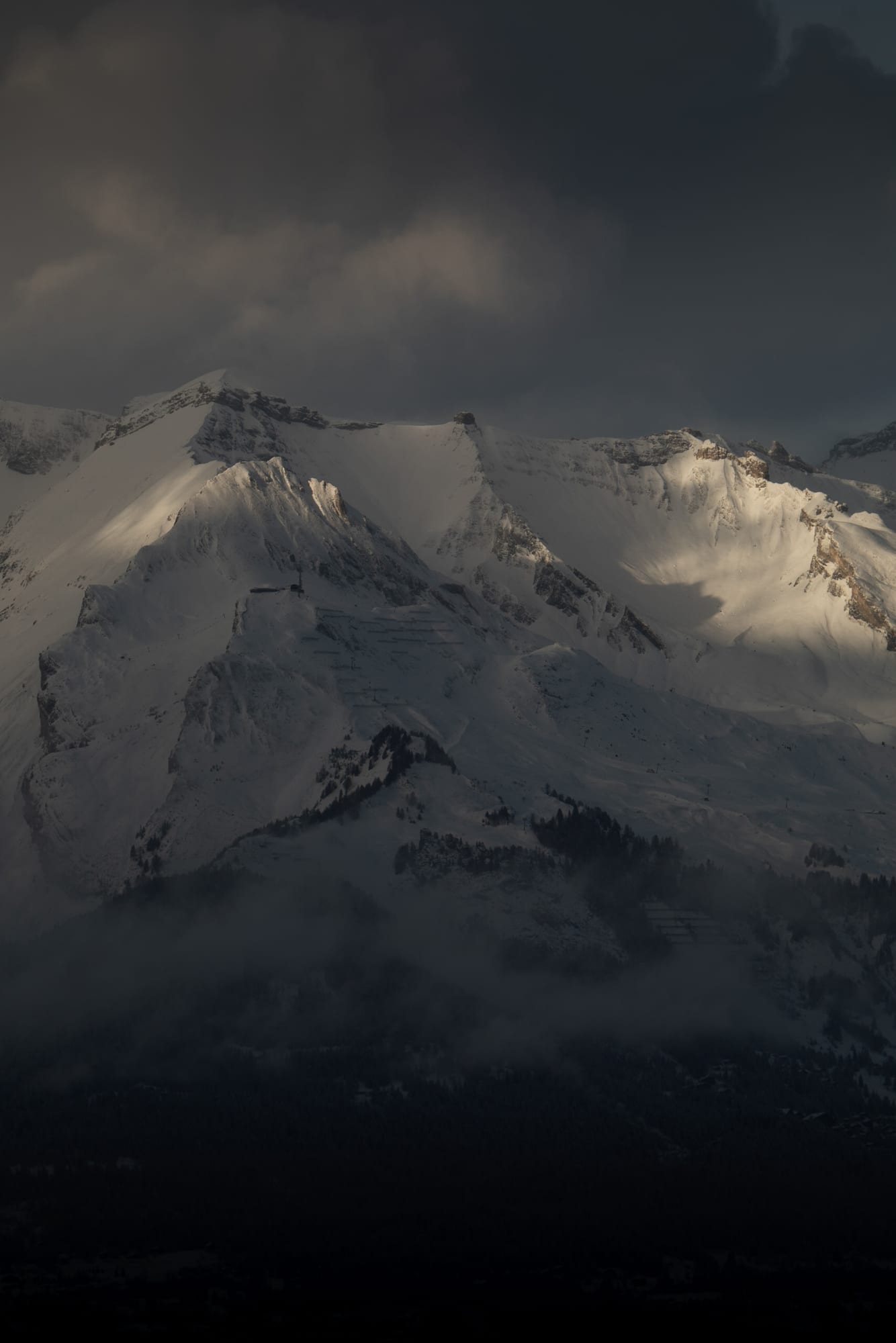 A snow peak glowing pink with alpenglow at dusk against a darkening sky in the Berner Oberland.