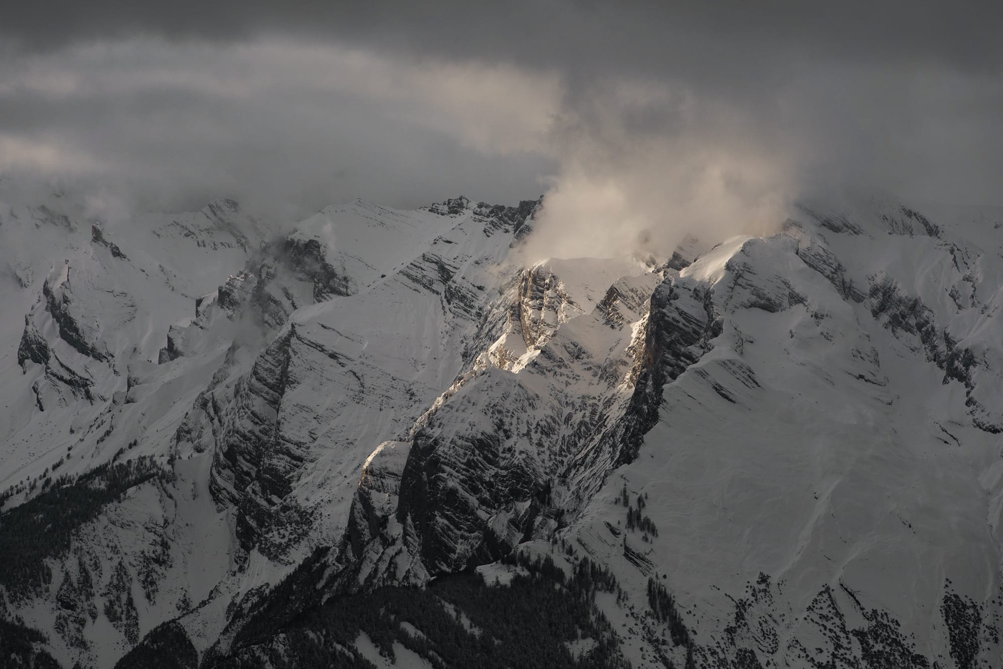 A snow-covered massif catching the last warm light of the day above valleys already in shadow, in Wallis.
